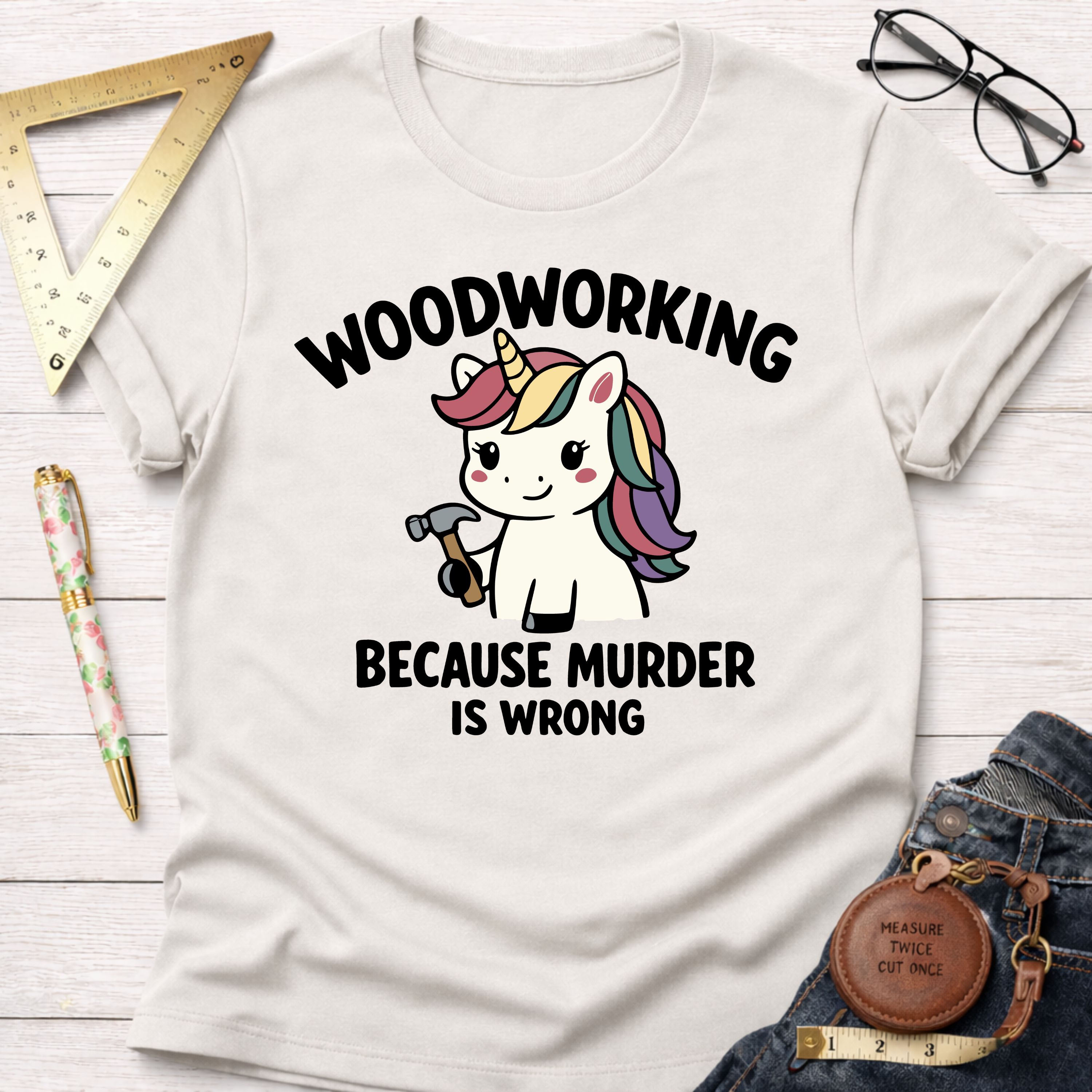 Women's funny woodworking graphic tee shirt for female woodworkers, makers, and DIY builders — Sawdust & Ponytails. White cotton tee with "Woodworking Because Murder Is Wrong" and a unicorn holding a hammer.
