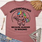 Women's funny woodworking graphic tee shirt for female woodworkers, makers, and DIY builders — Sawdust & Ponytails. Mauve cotton tee with a "Woodworking Because Murder Is Wrong" graphic featuring an angry unicorn holding a hammer and saw.