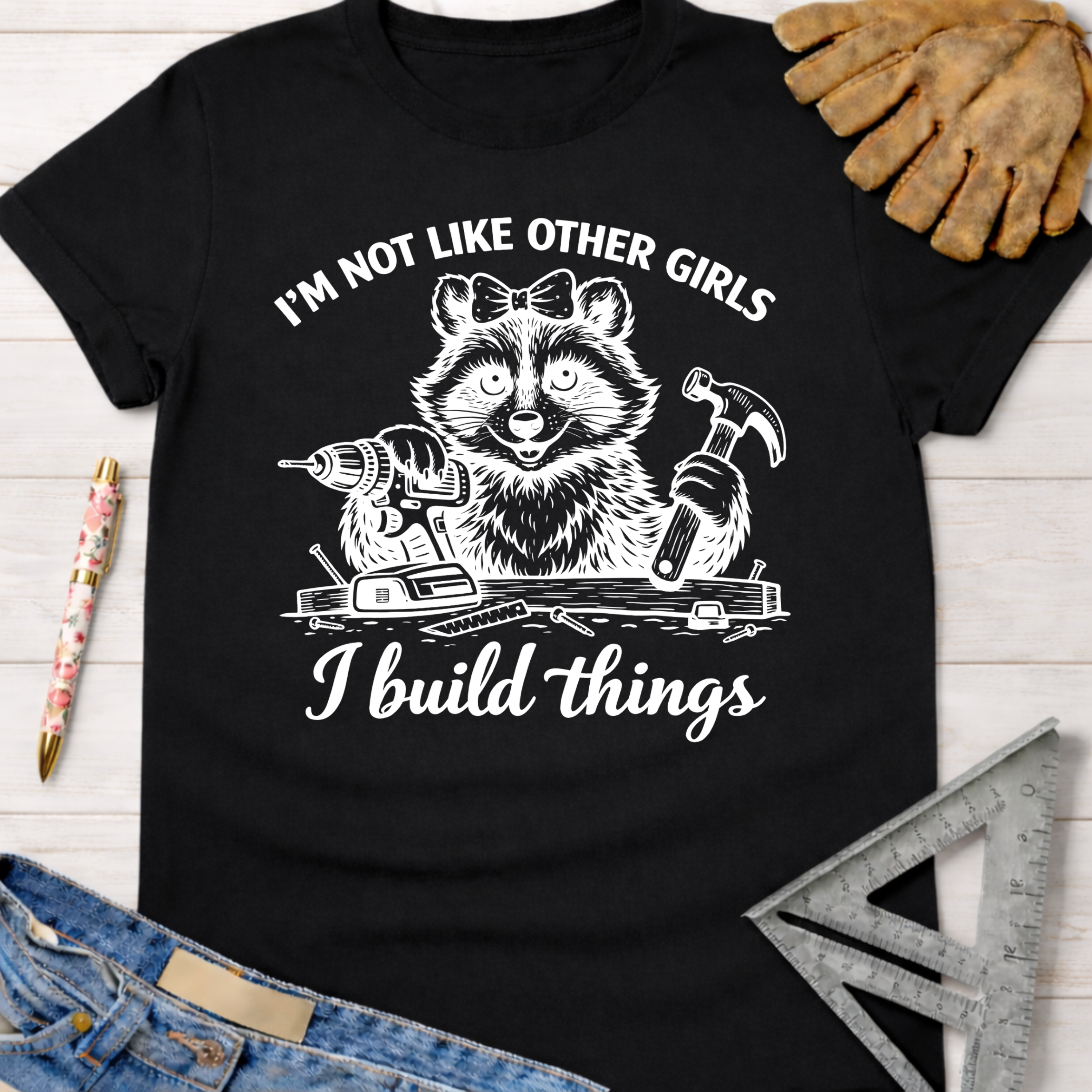 Black women's funny woodworking graphic tee with a raccoon holding a drill and hammer, "I build things" text.