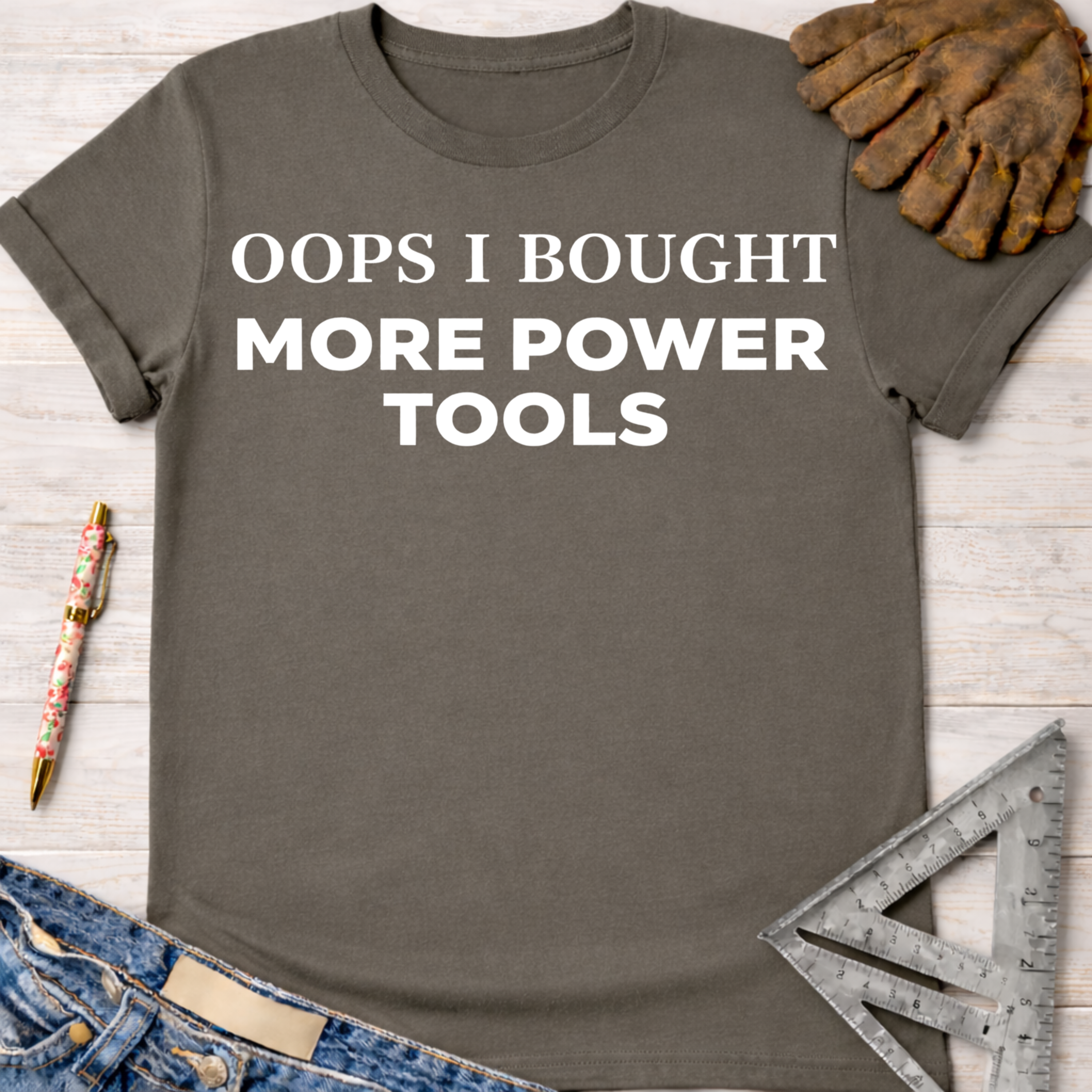 Women's funny woodworking graphic tee shirt for female woodworkers, makers, and DIY builders — Sawdust & Ponytails. Dark gray t-shirt with "OOPS I BOUGHT MORE POWER TOOLS" in white text.