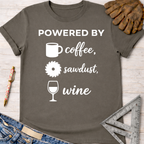 Women's funny woodworking graphic tee shirt for female woodworkers, makers, and DIY builders — Sawdust & Ponytails. Dark gray cotton tee with "POWERED BY coffee, sawdust, wine" text and icons.