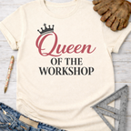 Women's funny woodworking graphic tee shirt for female woodworkers, makers, and DIY builders — Sawdust & Ponytails. Cream t-shirt with "Queen OF THE WORKSHOP" in pink and black.