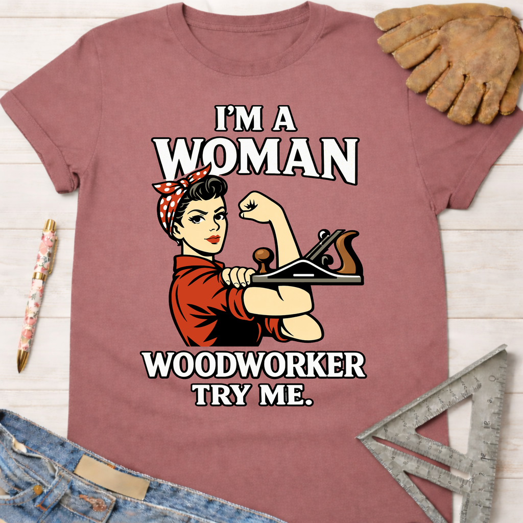 Women's funny woodworking graphic tee shirt for female woodworkers, makers, and DIY builders — Sawdust & Ponytails. Mauve cotton tee with Rosie the Riveter holding a wood plane, "I'm a Woman Woodworker Try Me" text.
