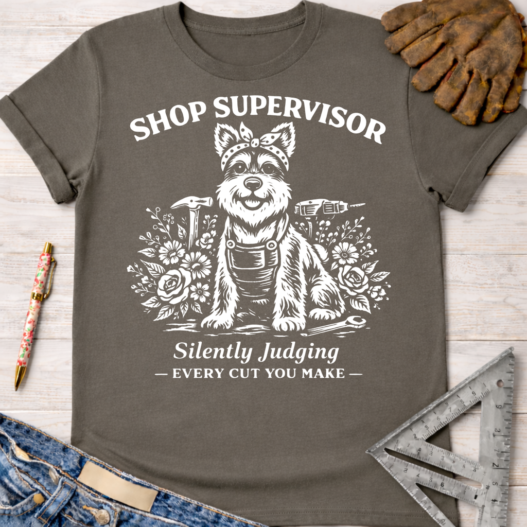 Women's funny woodworking graphic tee shirt for female woodworkers, makers, and DIY builders — Sawdust & Ponytails. Dark gray cotton tee with a white graphic of a dog in a bandana and overalls, surrounded by tools and flowers, with text "Shop Supervisor Silently Judging Every Cut You Make.