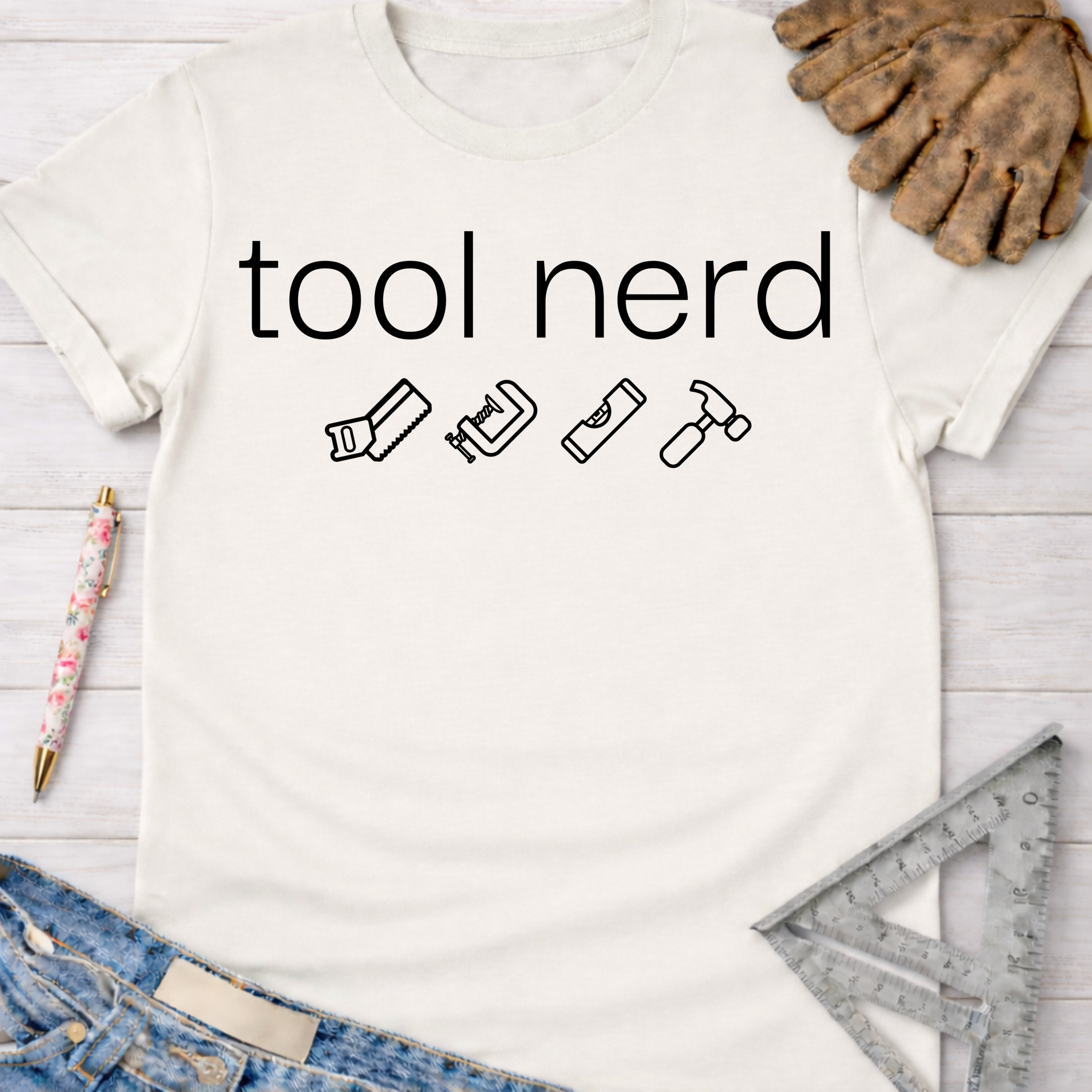 Women's funny woodworking graphic tee shirt for female woodworkers, makers, and DIY builders — Sawdust & Ponytails. White cotton tee with "tool nerd" text and saw, clamp, level, hammer icons.
