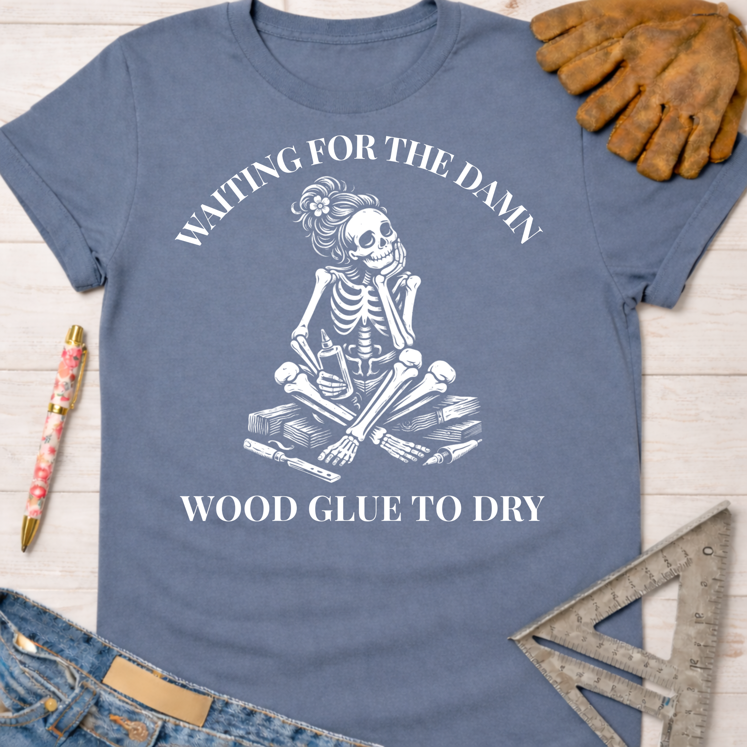 Women's funny woodworking graphic tee shirt for female woodworkers, makers, and DIY builders — Sawdust & Ponytails. Blue cotton t-shirt with a white skeleton graphic waiting for glue to dry.