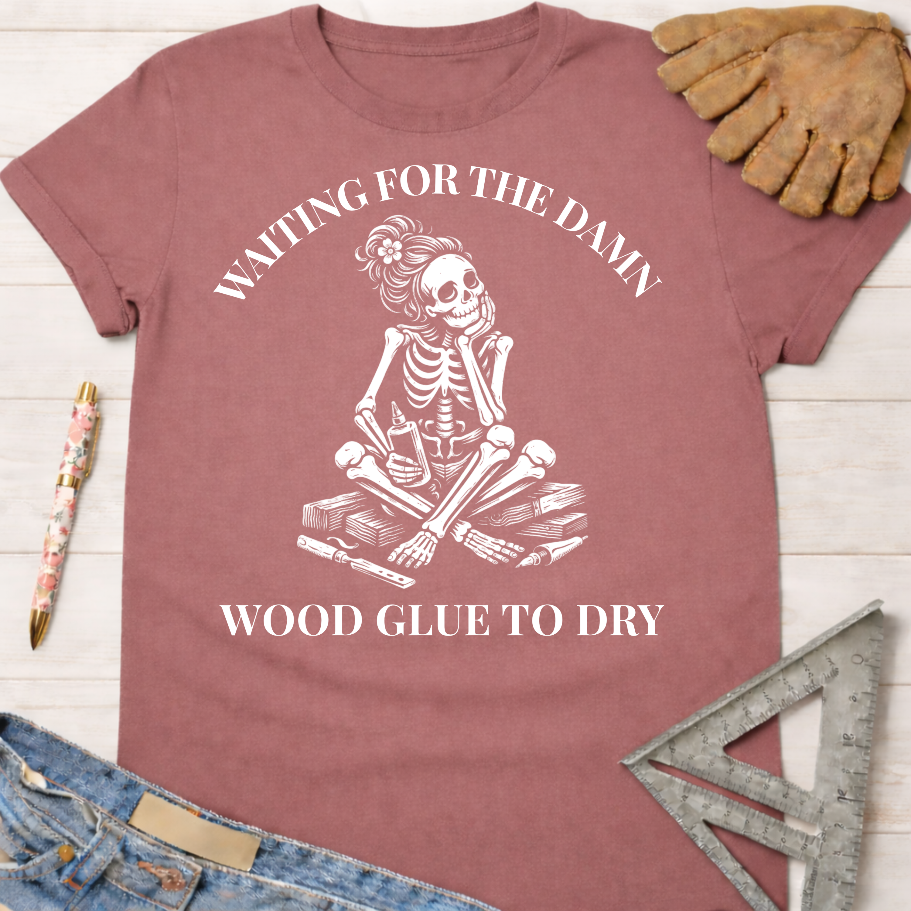 Women's funny woodworking graphic tee shirt for female woodworkers, makers, and DIY builders — Sawdust & Ponytails. Mauve t-shirt with a skeleton impatiently waiting for wood glue to dry.