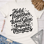 Women's funny woodworking graphic tee shirt for female woodworkers, makers, and DIY builders — Sawdust & Ponytails. Cream t-shirt with "Held Together by Wood Glue and Impure Thoughts" in black script.
