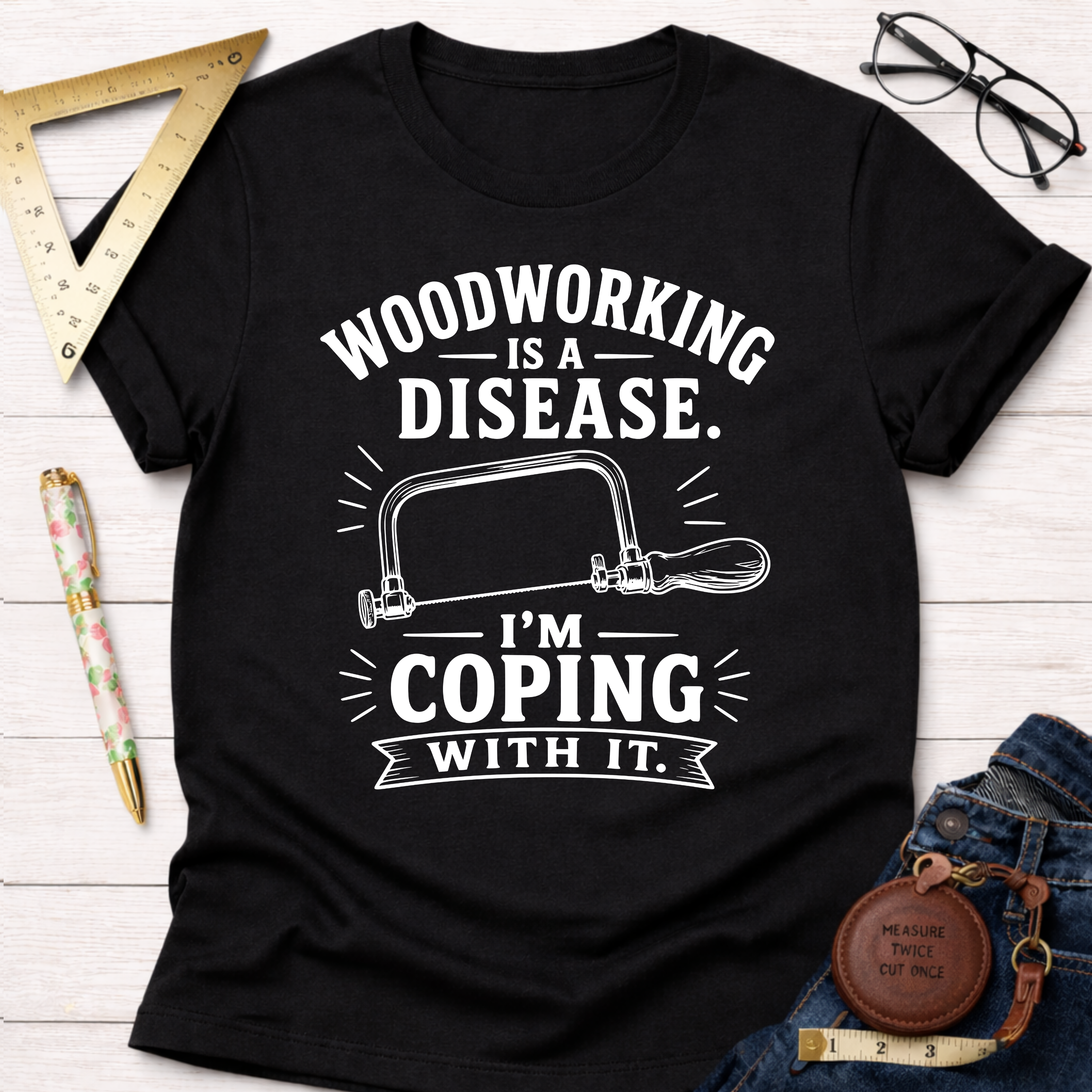 Women's funny woodworking graphic tee shirt for female woodworkers, makers, and DIY builders — Sawdust & Ponytails. Black cotton tee with "Woodworking Is A Disease. I'm Coping With It." text and a hand saw graphic.