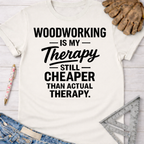 Women's funny woodworking graphic tee shirt for female woodworkers, makers, and DIY builders — Sawdust & Ponytails. White cotton tee with "Woodworking Is My Therapy Still Cheaper Than Actual Therapy" in black text.